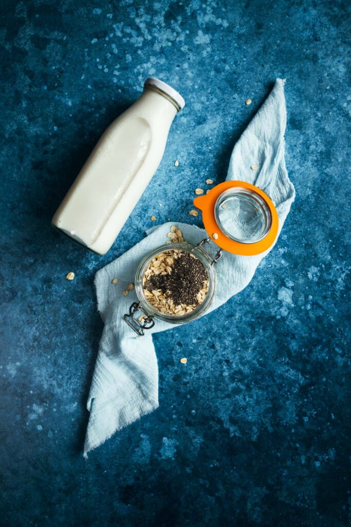A bottle of milk and oats on a blue background.