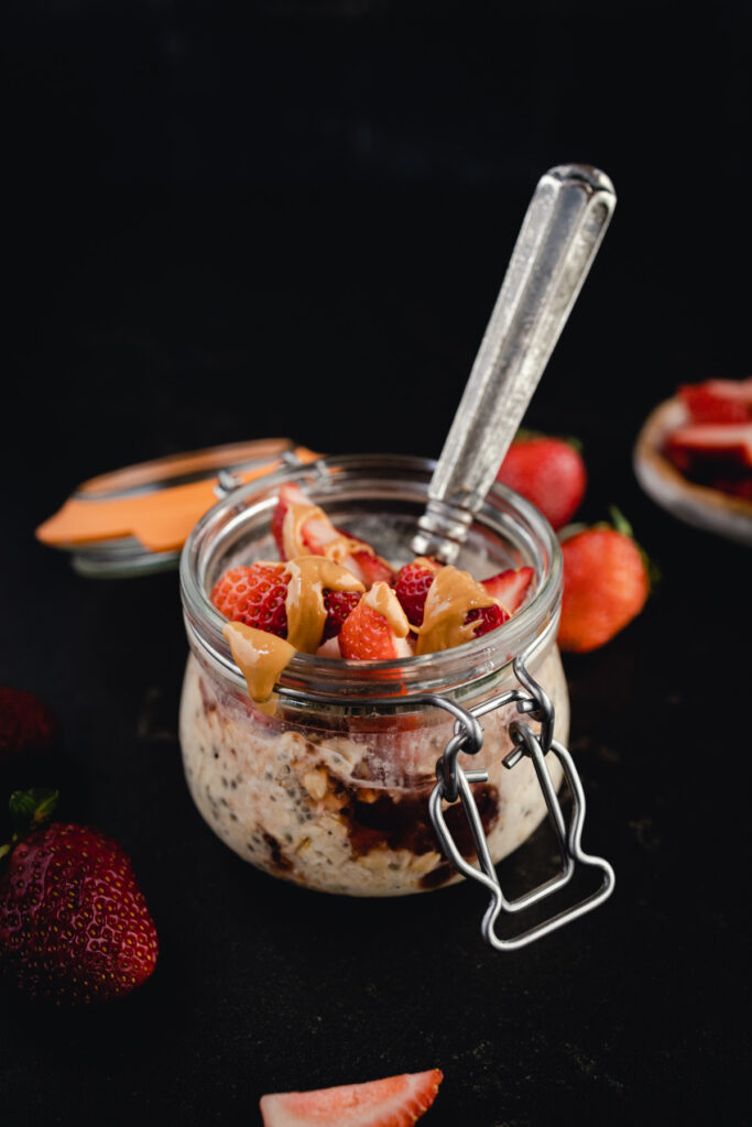 A glass jar filled with oatmeal and strawberries.