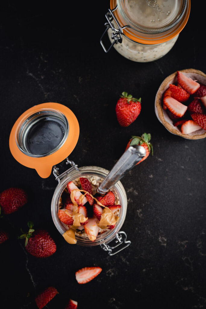 A bowl of oats with strawberries and a spoon.