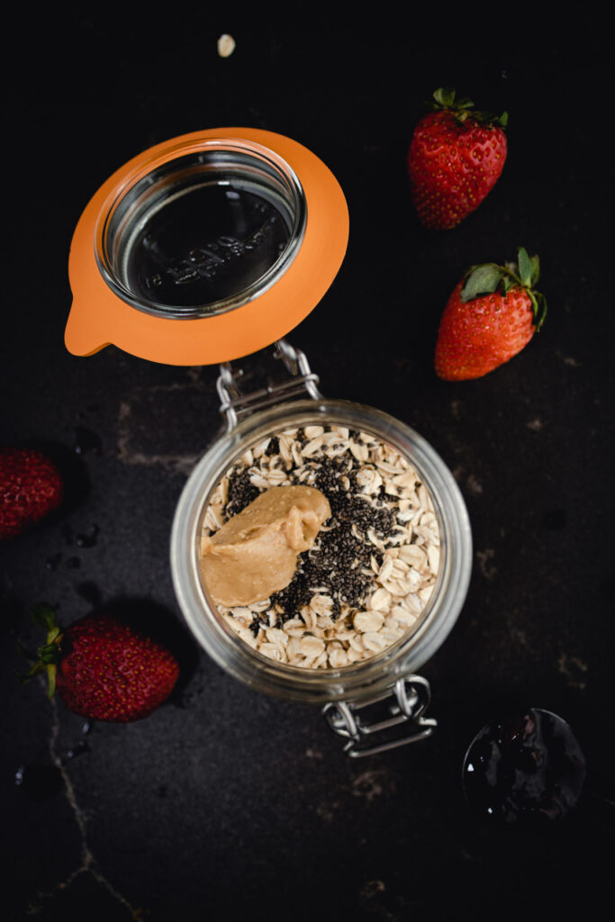 A bowl of oats and strawberries in a jar.