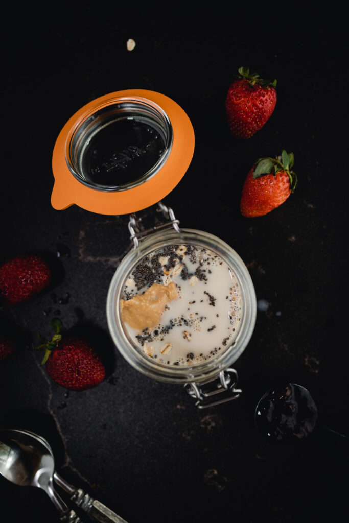 Oatmeal in a jar with strawberries and a spoon.