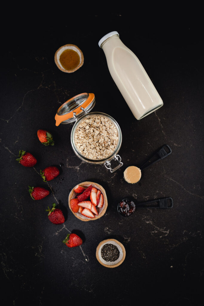 A bowl of oats, strawberries and a bottle of milk.