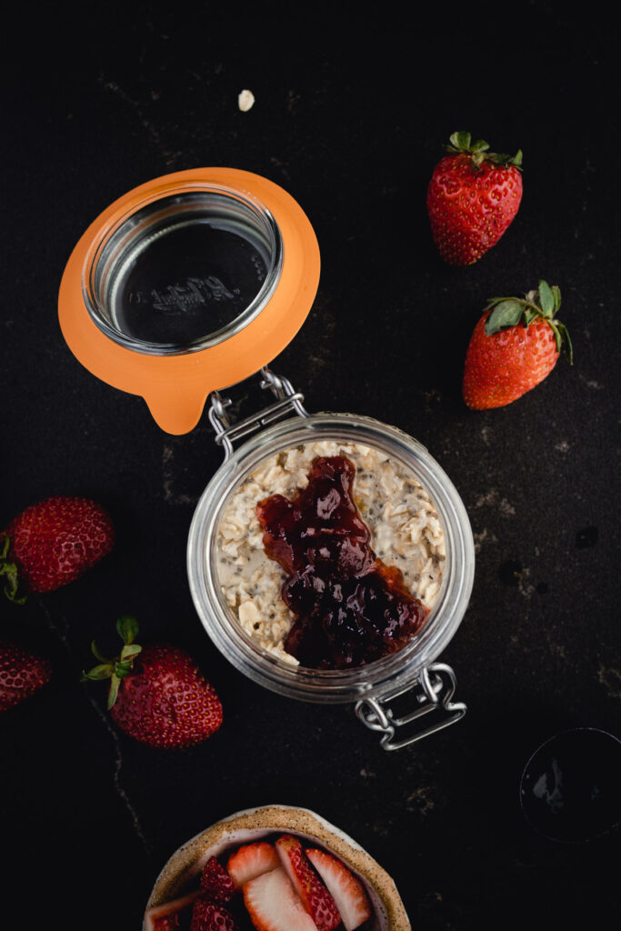 A bowl of oats with strawberries and jam.