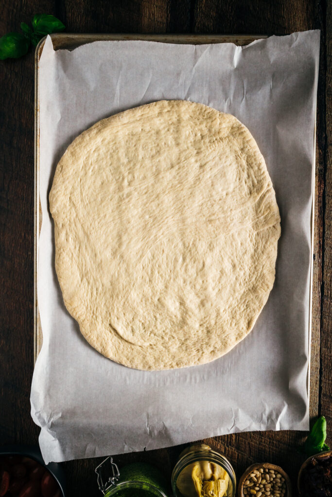 Homemade pizza dough on a baking sheet.