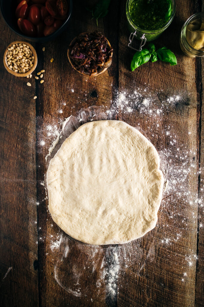 An image of a pizza dough on a wooden table.