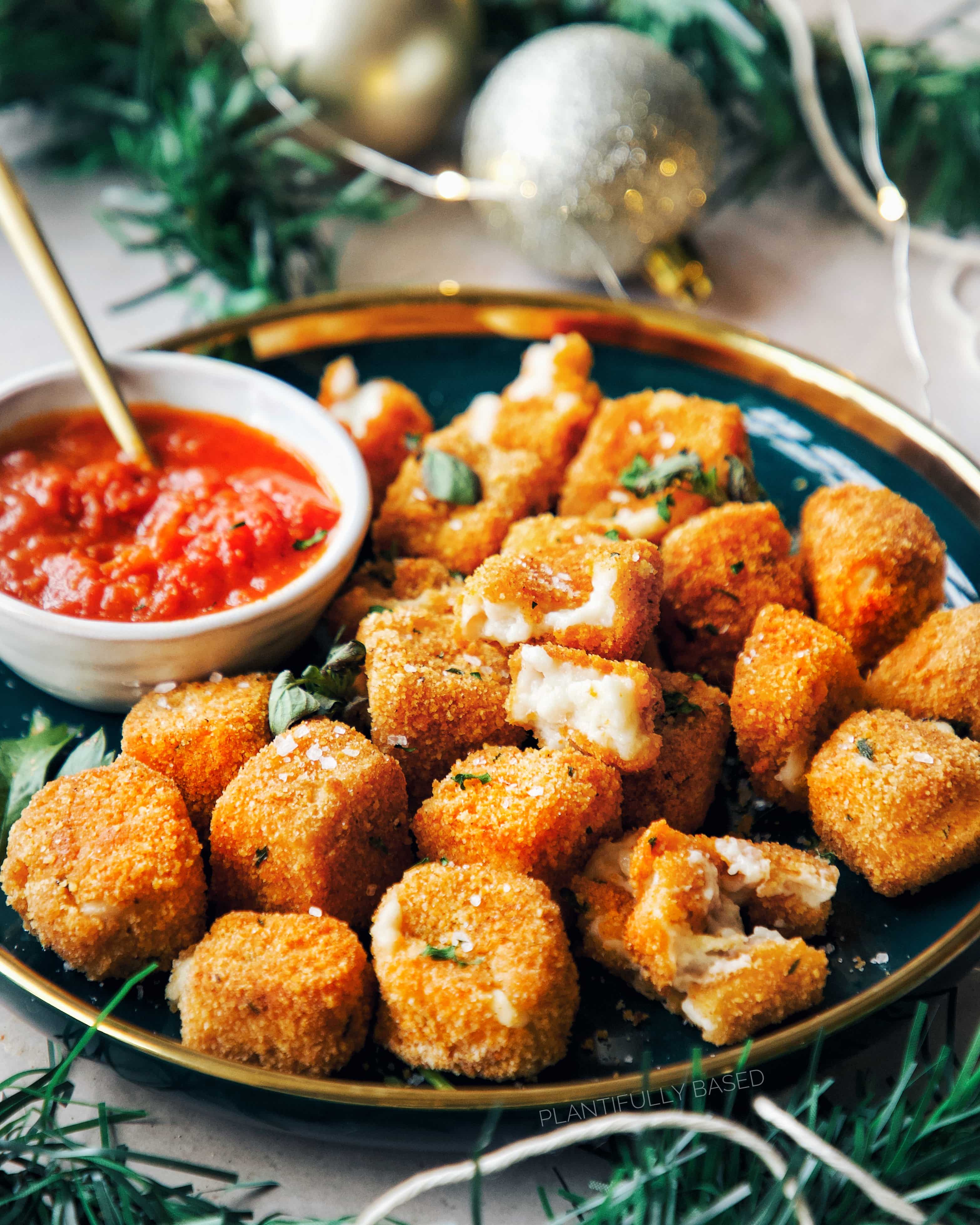 Vegan mozzarella bites on a plate with dipping sauce, perfect for game day or Super Bowl recipes.