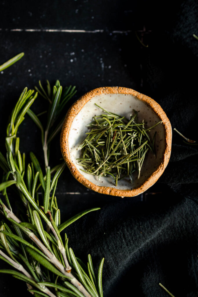 Rosemary in a bowl on a black background.