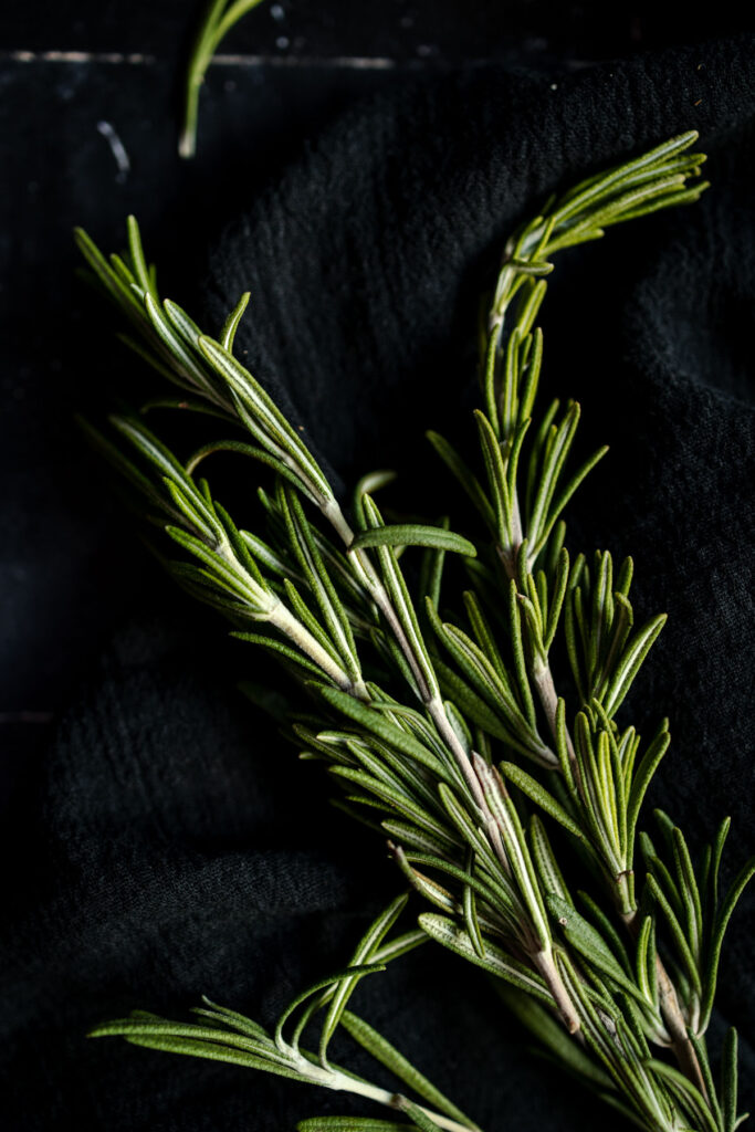 A bunch of rosemary on a black cloth.