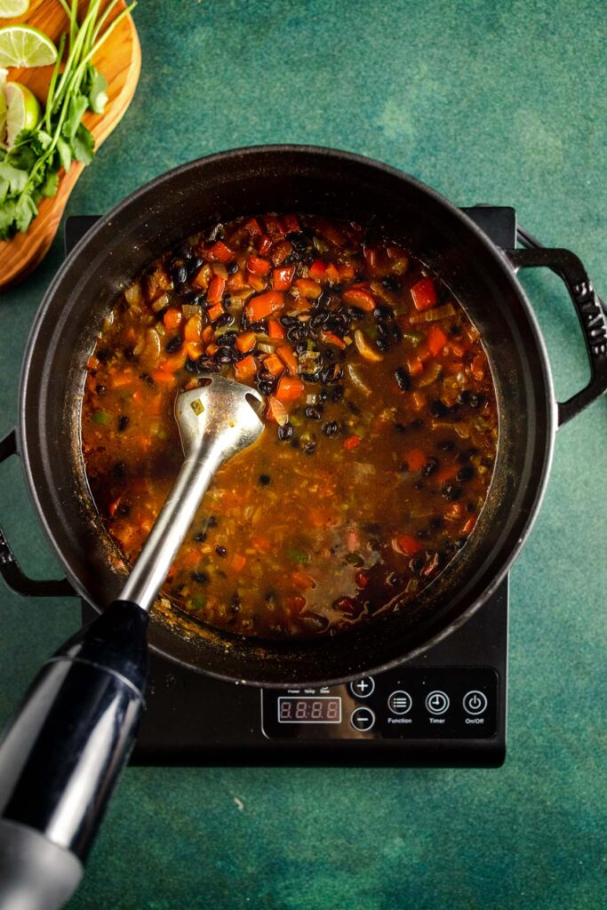 A pot of soup on a stove top with a spatula.