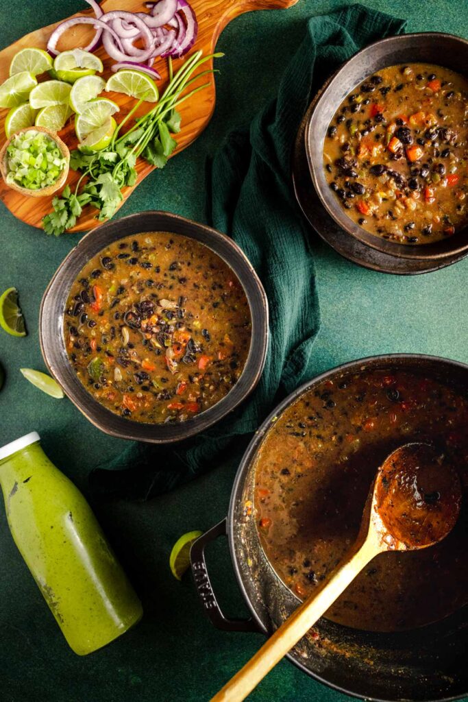 Three bowls of black bean soup on a green table.
