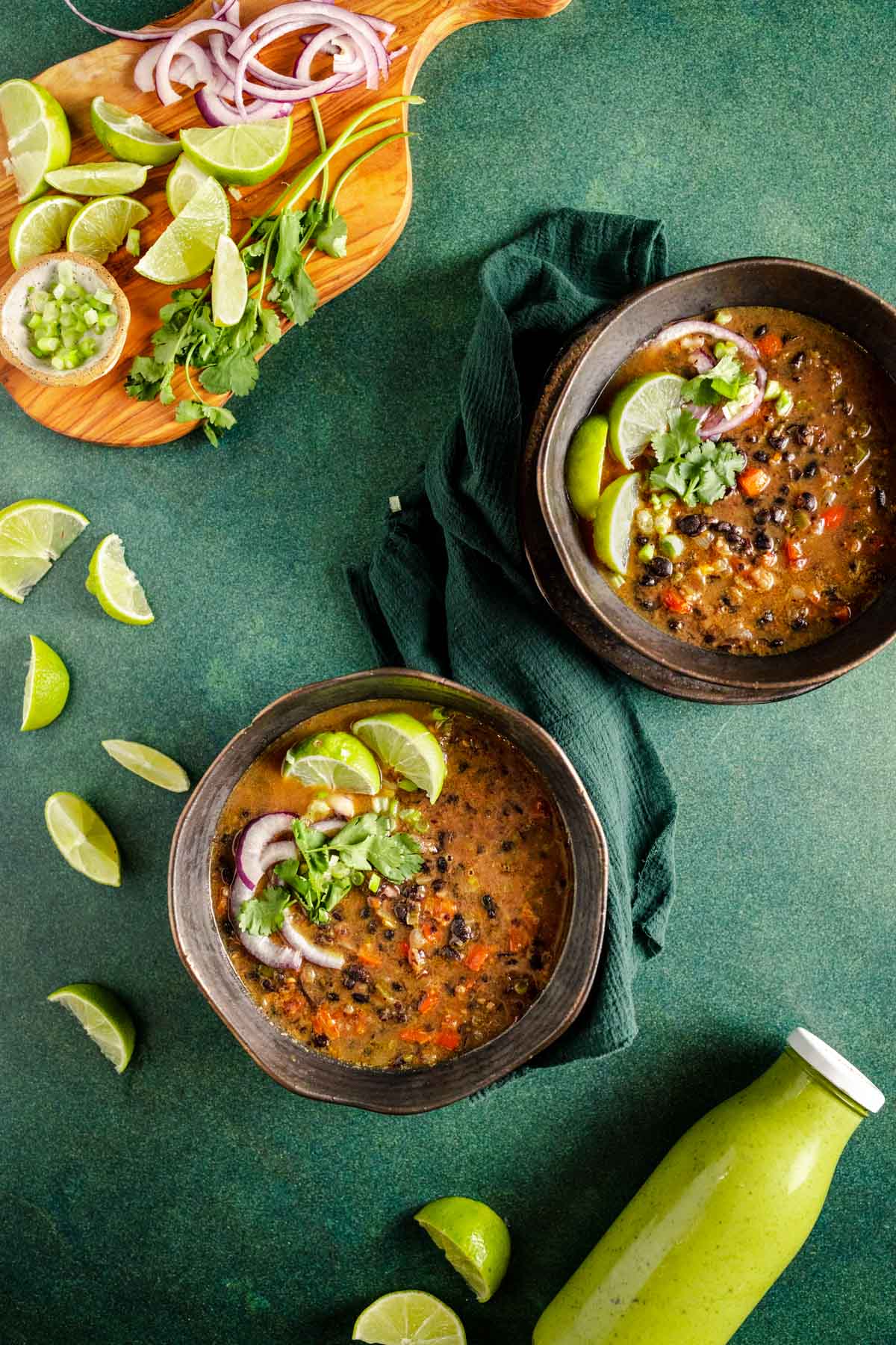 Two bowls of black bean soup on a green background.