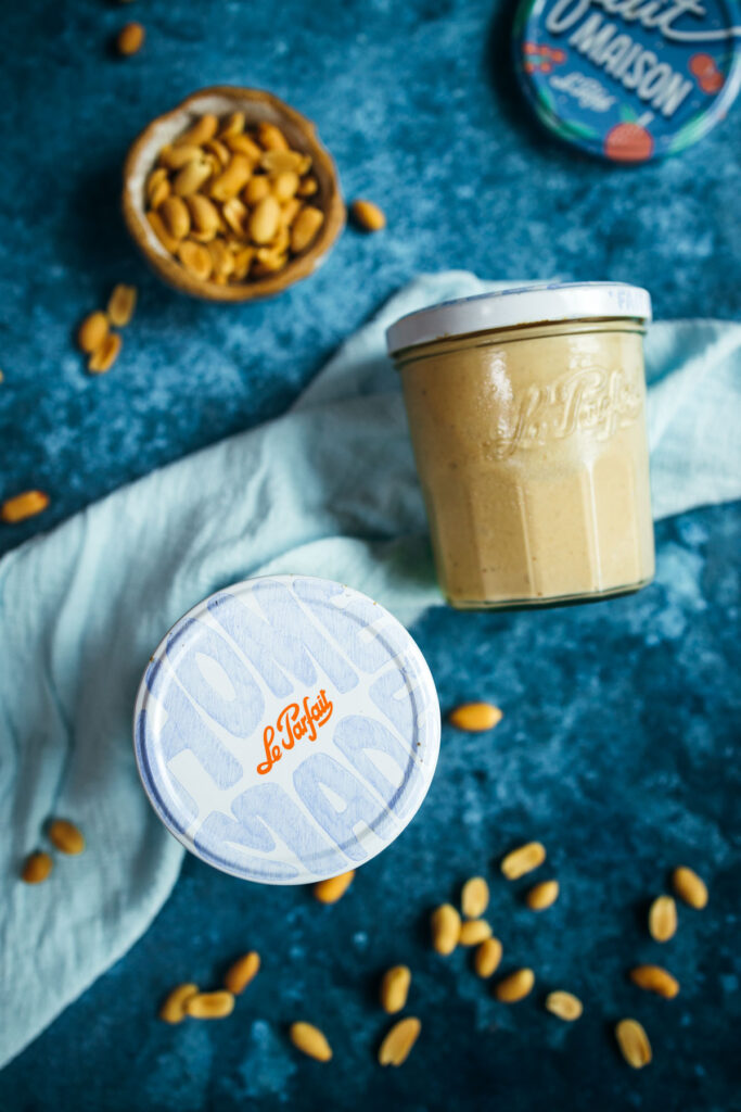 A jar of peanut butter and a bowl of peanuts.