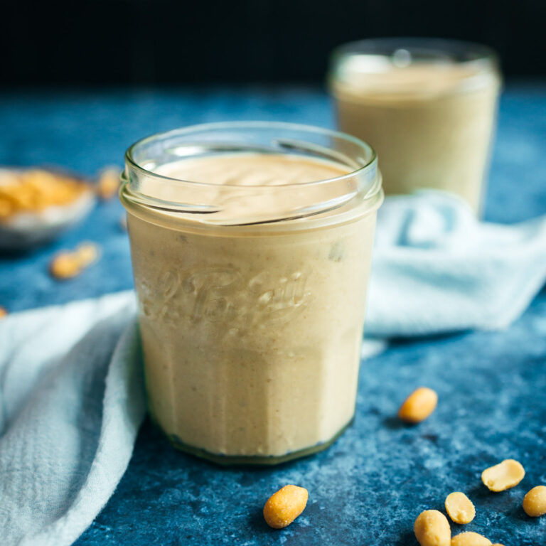 Two jars of peanut butter smoothie on a blue background.