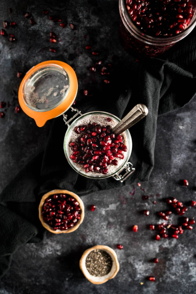 Pomegranate seeds and spices on a black background.