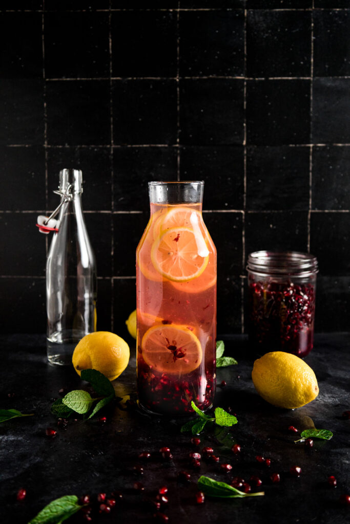 A glass of pomegranate juice with lemons and mint.