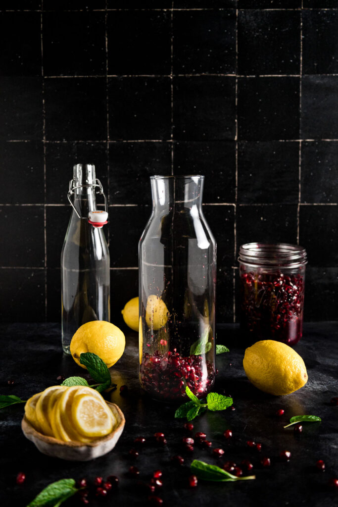 A glass jar with lemons and pomegranate.
