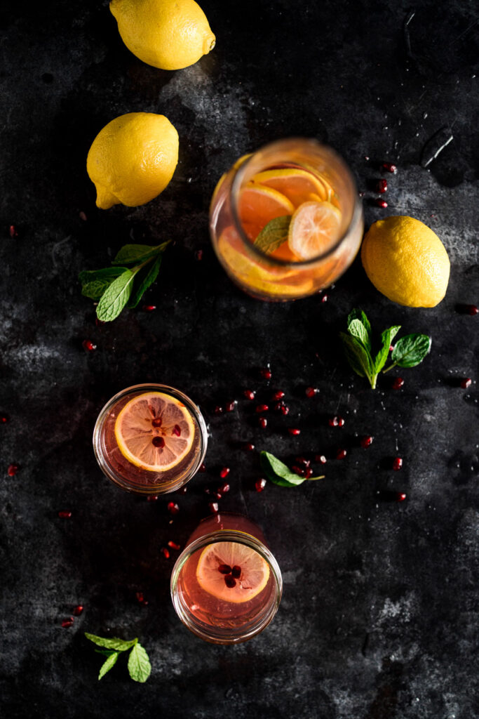 Pomegranate lemonade with pomegranate slices and mint leaves.