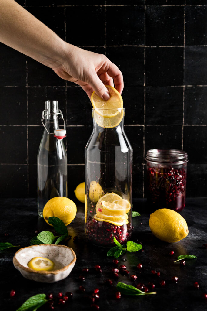 A hand is pouring lemon juice into a glass jar.