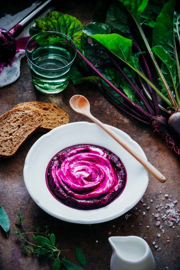 A bowl of beetroot soup with bread and vegetables.