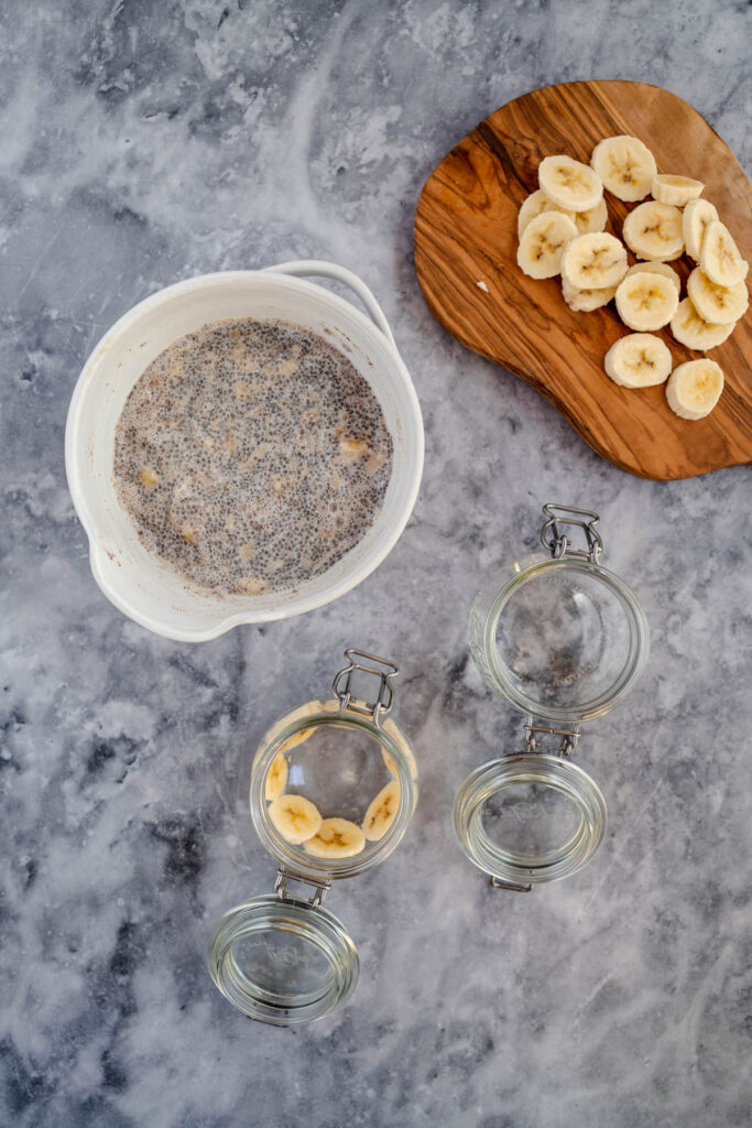 Preparation of banana chia pudding with ingredients laid out on marble surface.