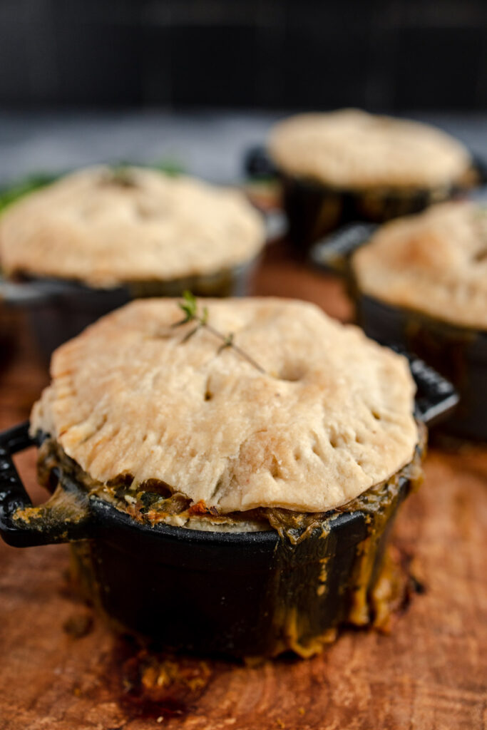 Individual pot pies with golden crusts garnished with a sprig of rosemary.