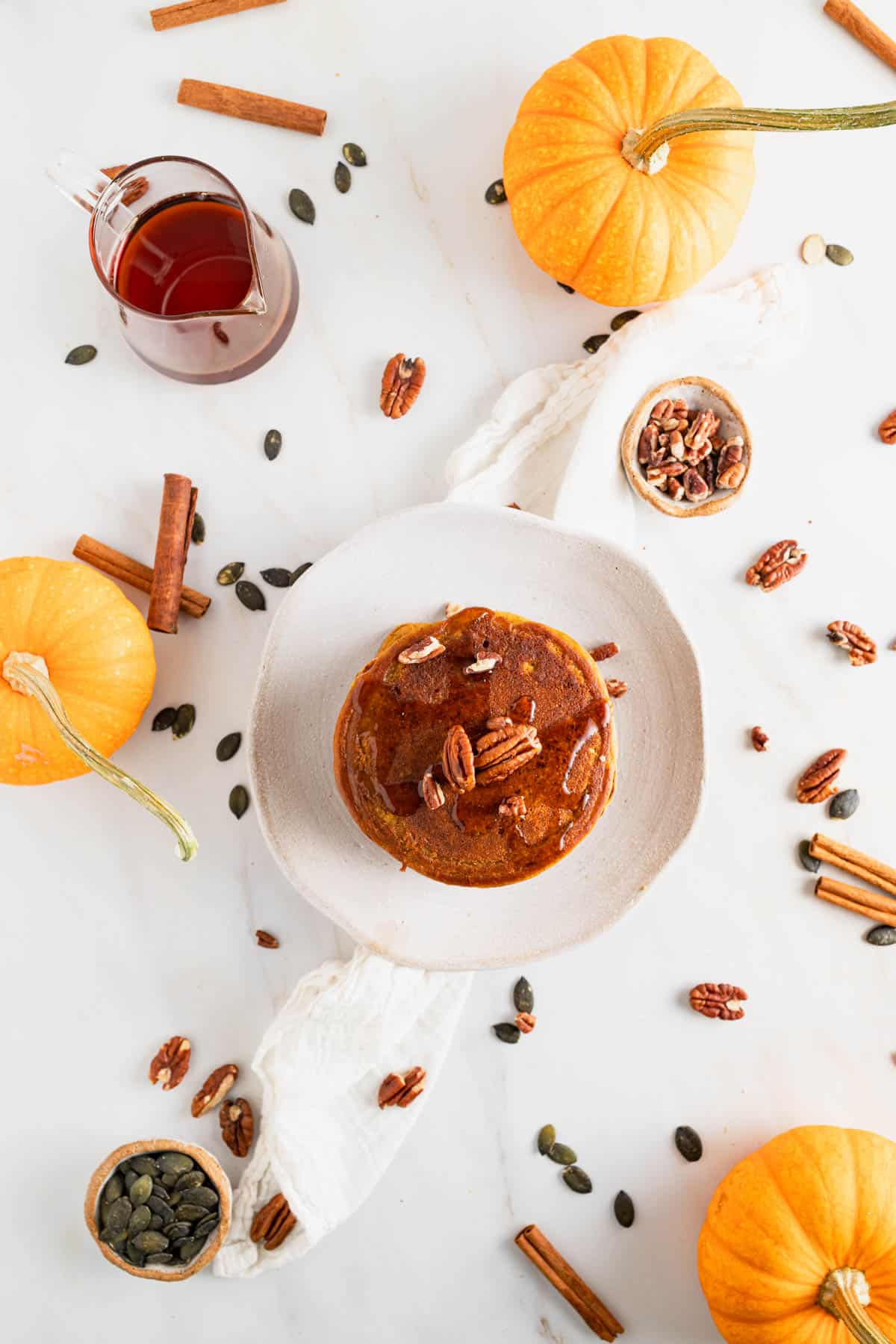 Flatlay of pumpkin protein pancakes on a white marble table.