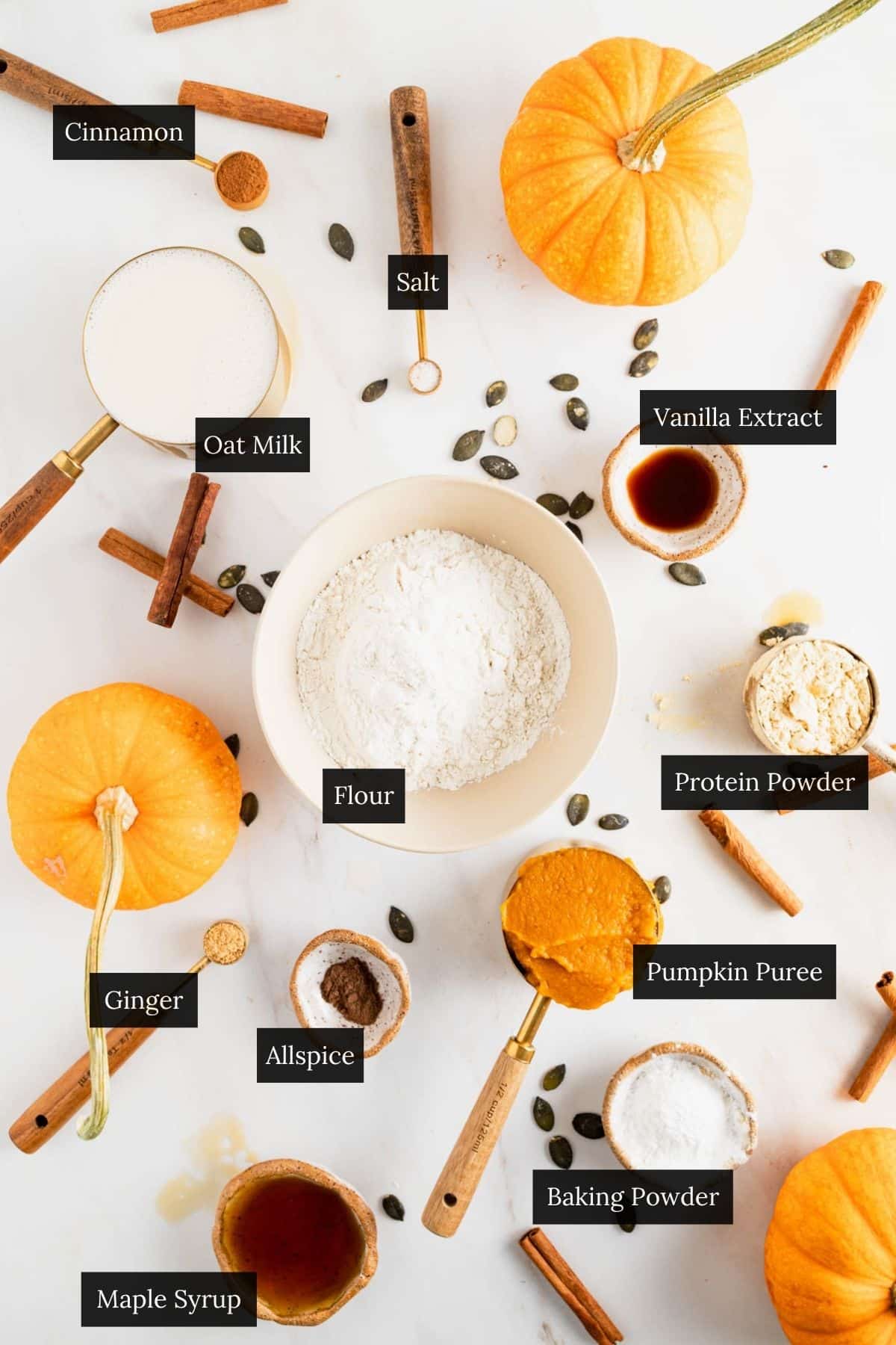 Ingredients for pumpkin pancakes with protein on a white marble surface with each ingredient labeled.
