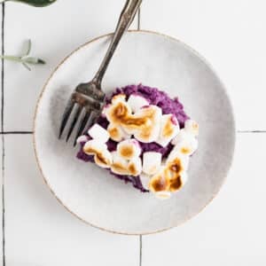 Vegan sweet potato casserole on a white plate with an antique fork.