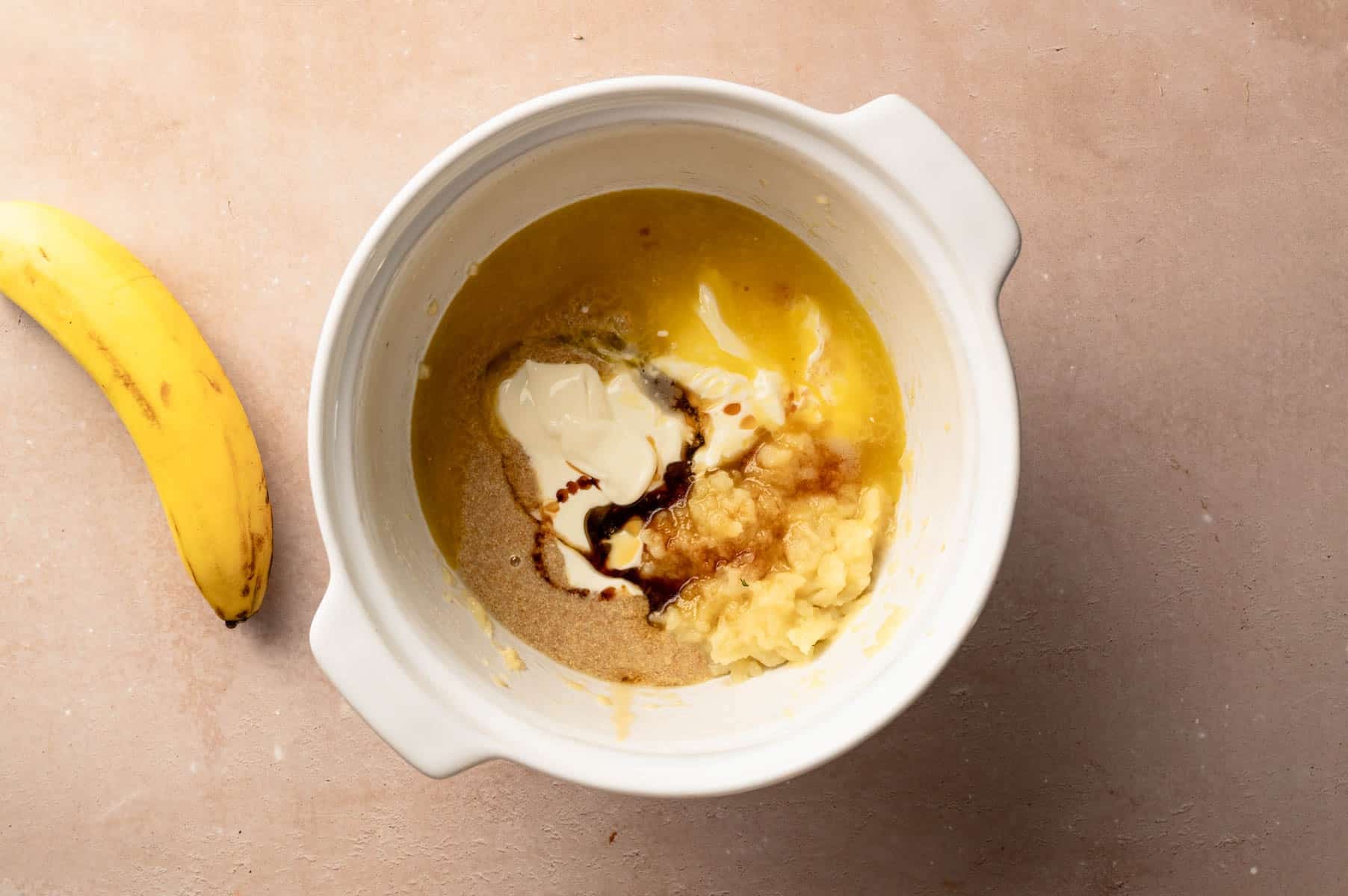 Wet ingredients for banana protein muffins in a large mixing bowl.