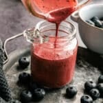 Easy blueberry salad dressing being poured into a glass jar.