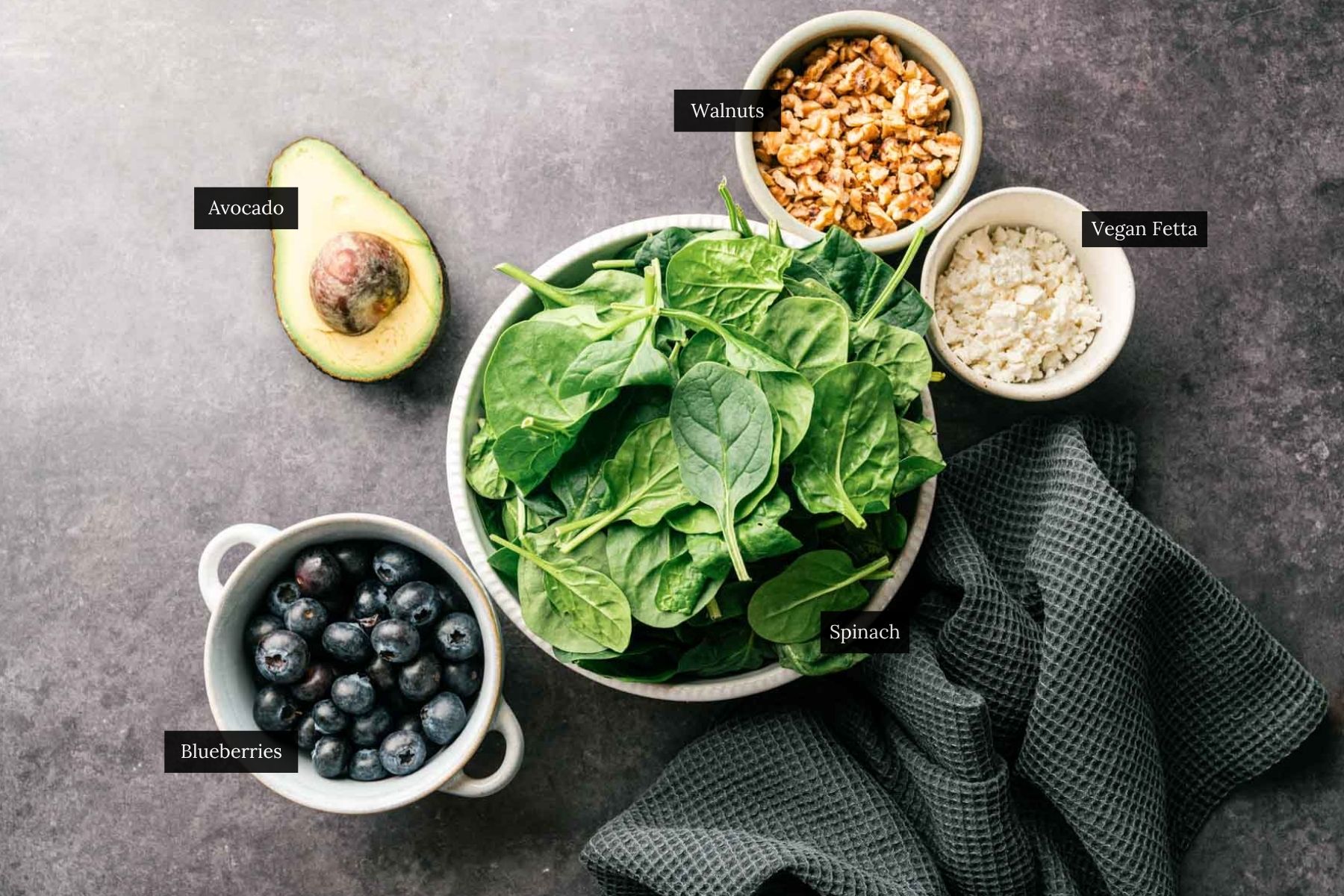 Ingredients for spinach and blueberry salad on a gray counter.