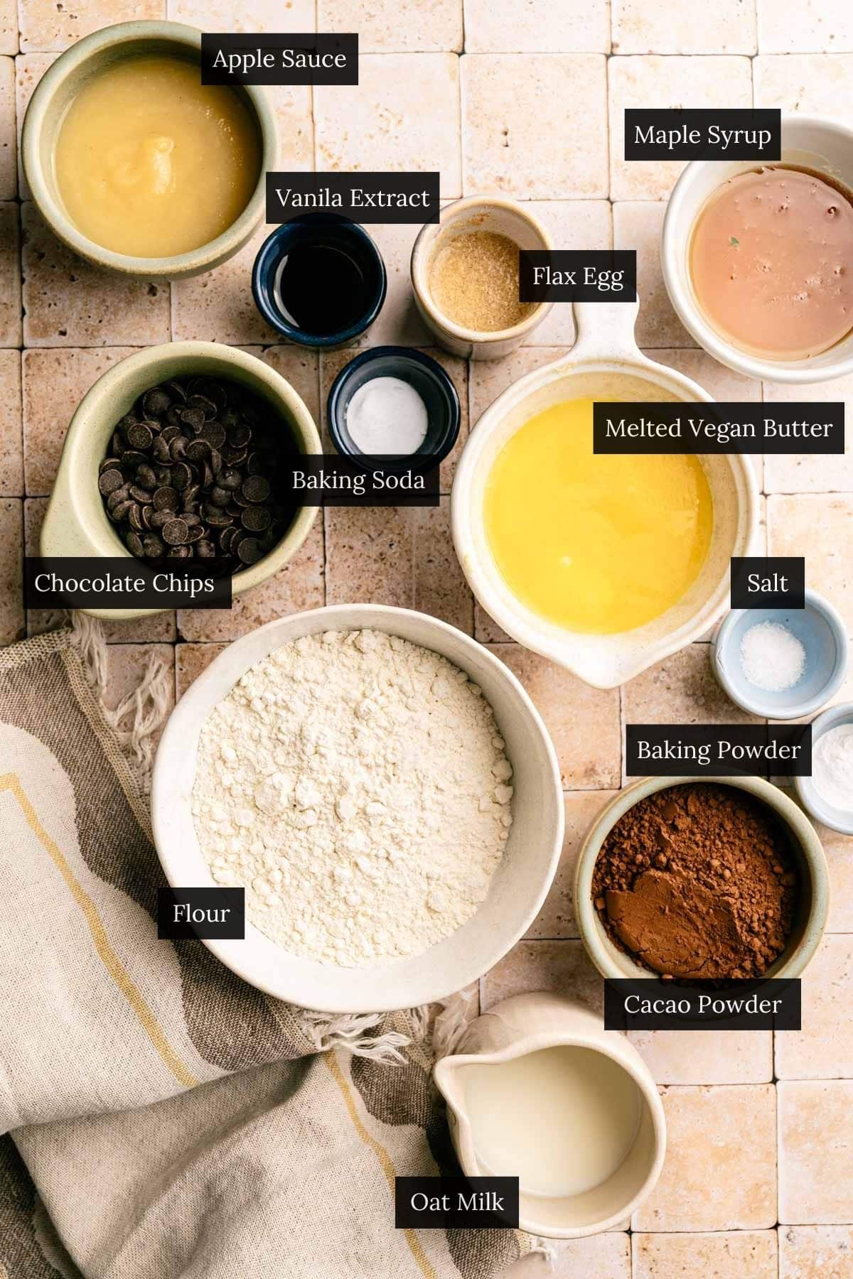 Ingredients for homemade chocolate muffins with chocolate chips on a tiled surface.