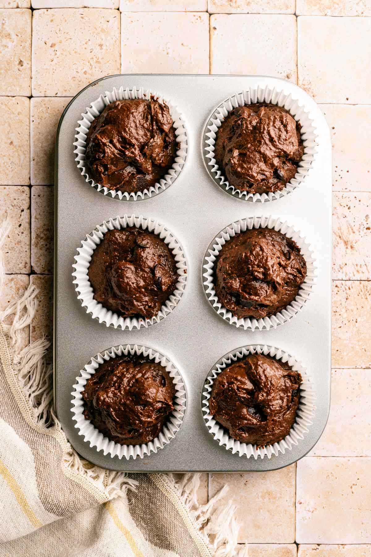 Chocolate muffins batter in a muffin tin.