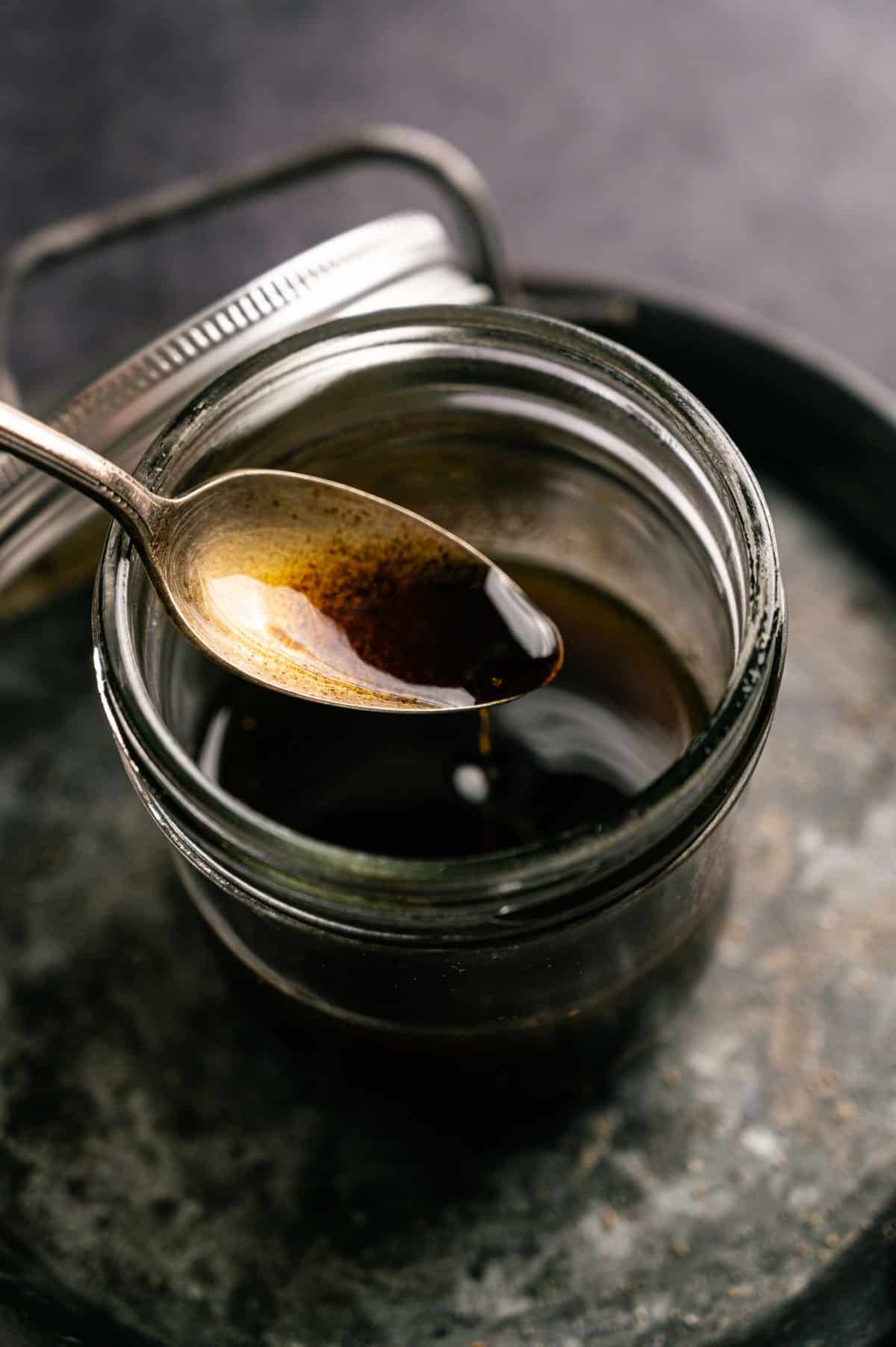 Balsamic maple vinaigrette being spooned into a glass jar.