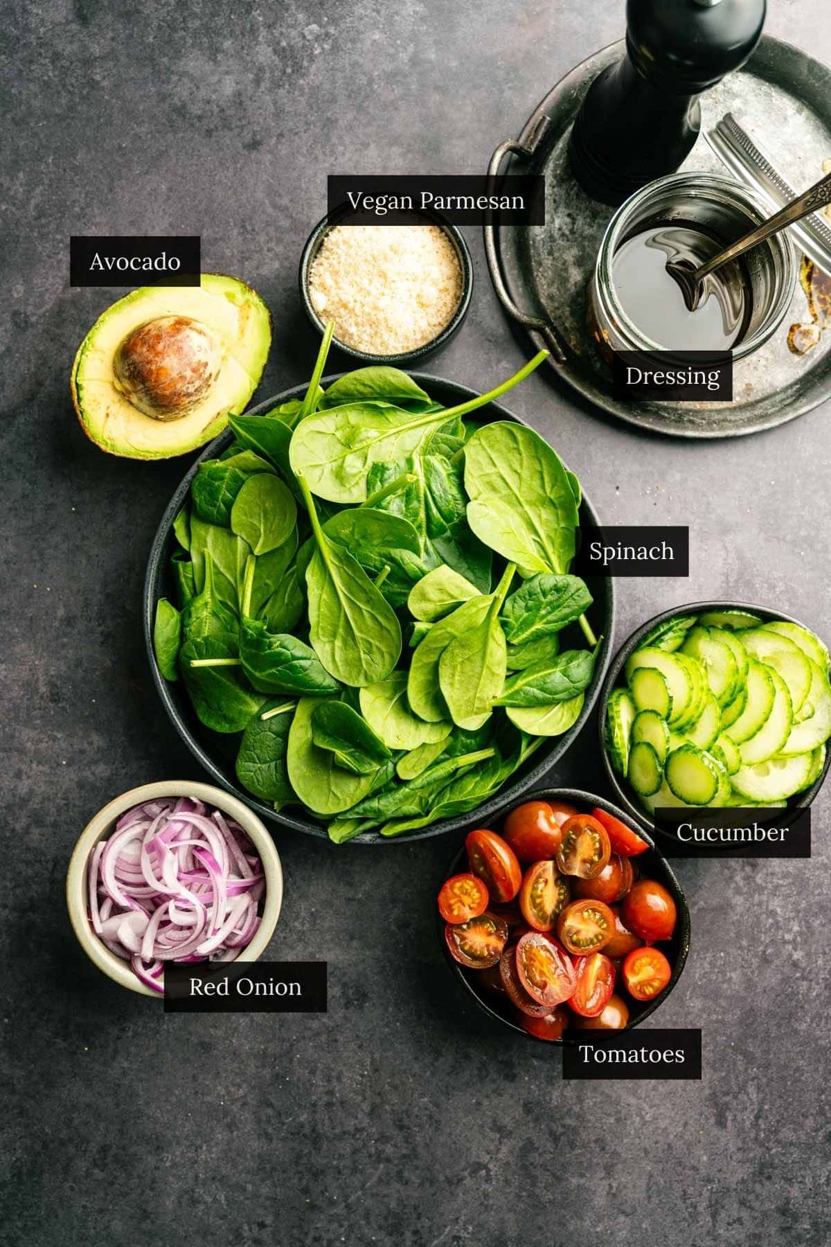 Ingredients for spinach and tomato salad recipe with each ingredient labeled.