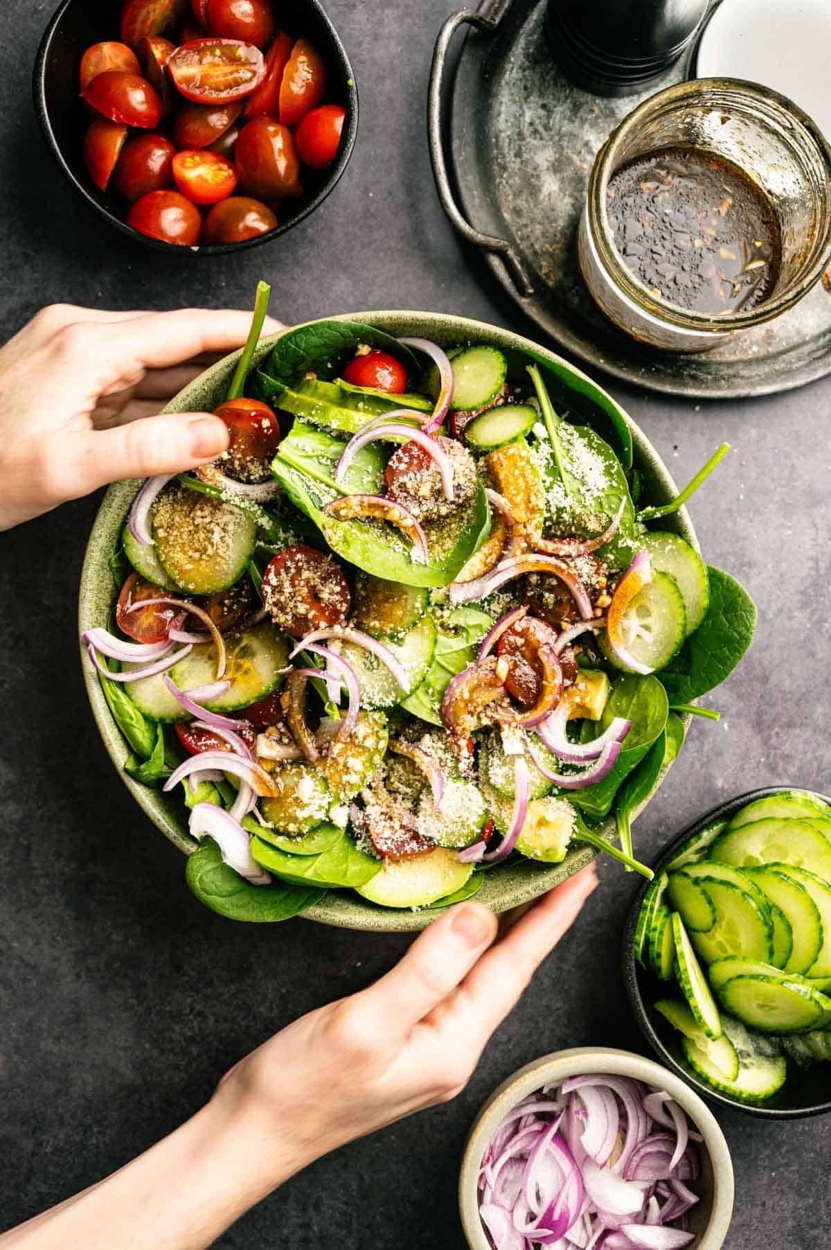 Woman grabbing tomato spinach salad.