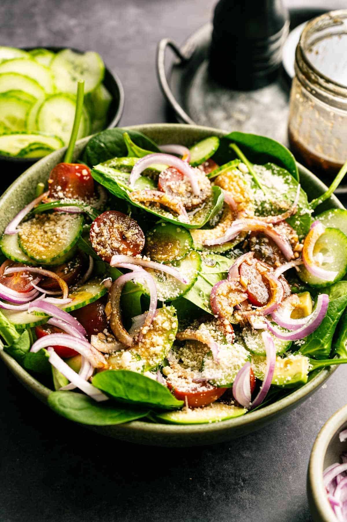 Spinach tomato salad with red onions and vegan parmesan on top.