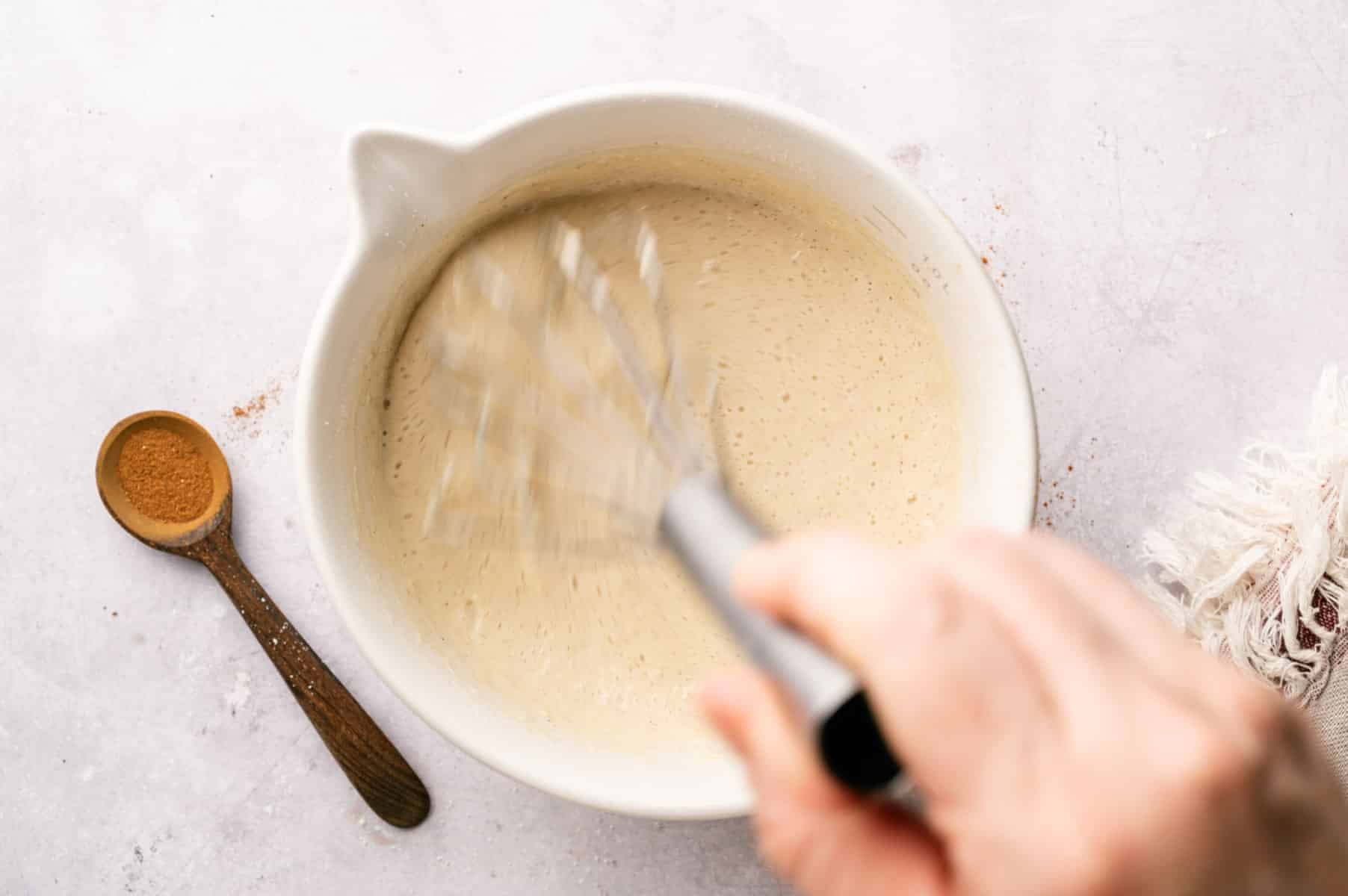 Wet ingredients in a large mixing bowl being whisk into the dry ingredients.