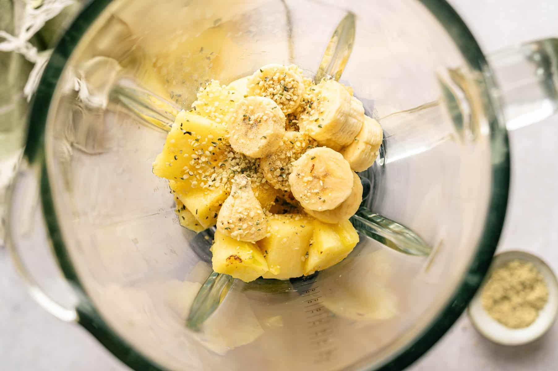 Ingredients for banana pineapple blueberry smoothie added to a blender.