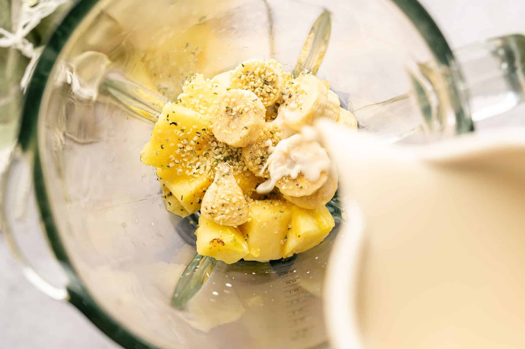 Ingredients for banana pineapple blueberry smoothie added to a blender.
