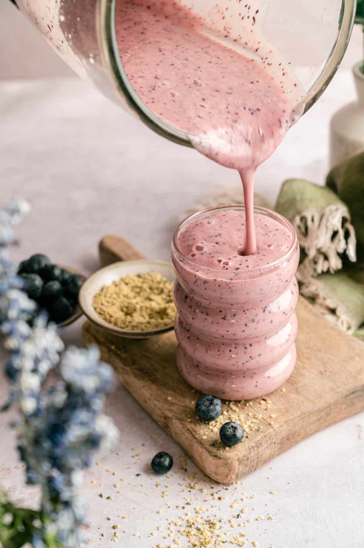 Pineapple and blueberry smoothie being poured into a cup.