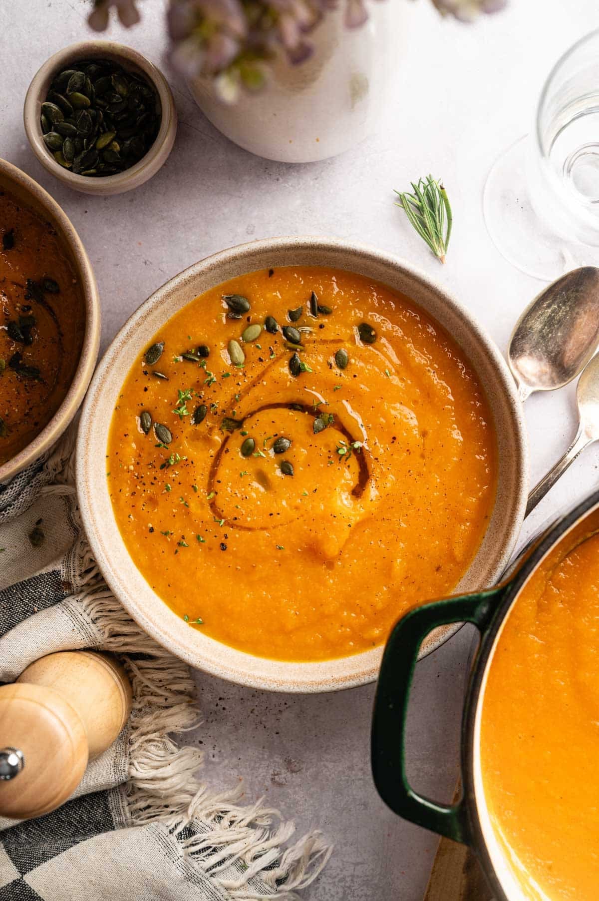 Large bowl of butternut carrot soup with a green Dutch oven next to it.