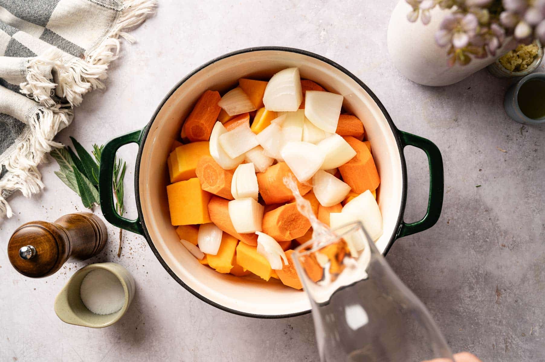 Chopped squash, carrots, onion, and water added to green Dutch oven.