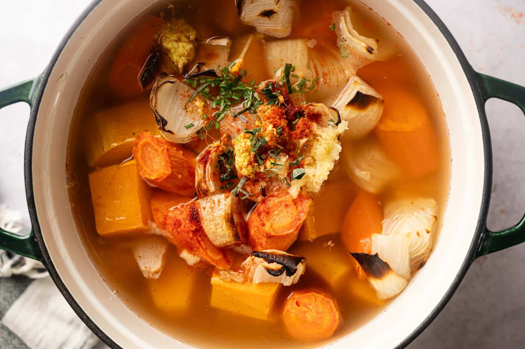 Veggie broth, herbs, salt, and pepper added to Dutch oven to simmer.